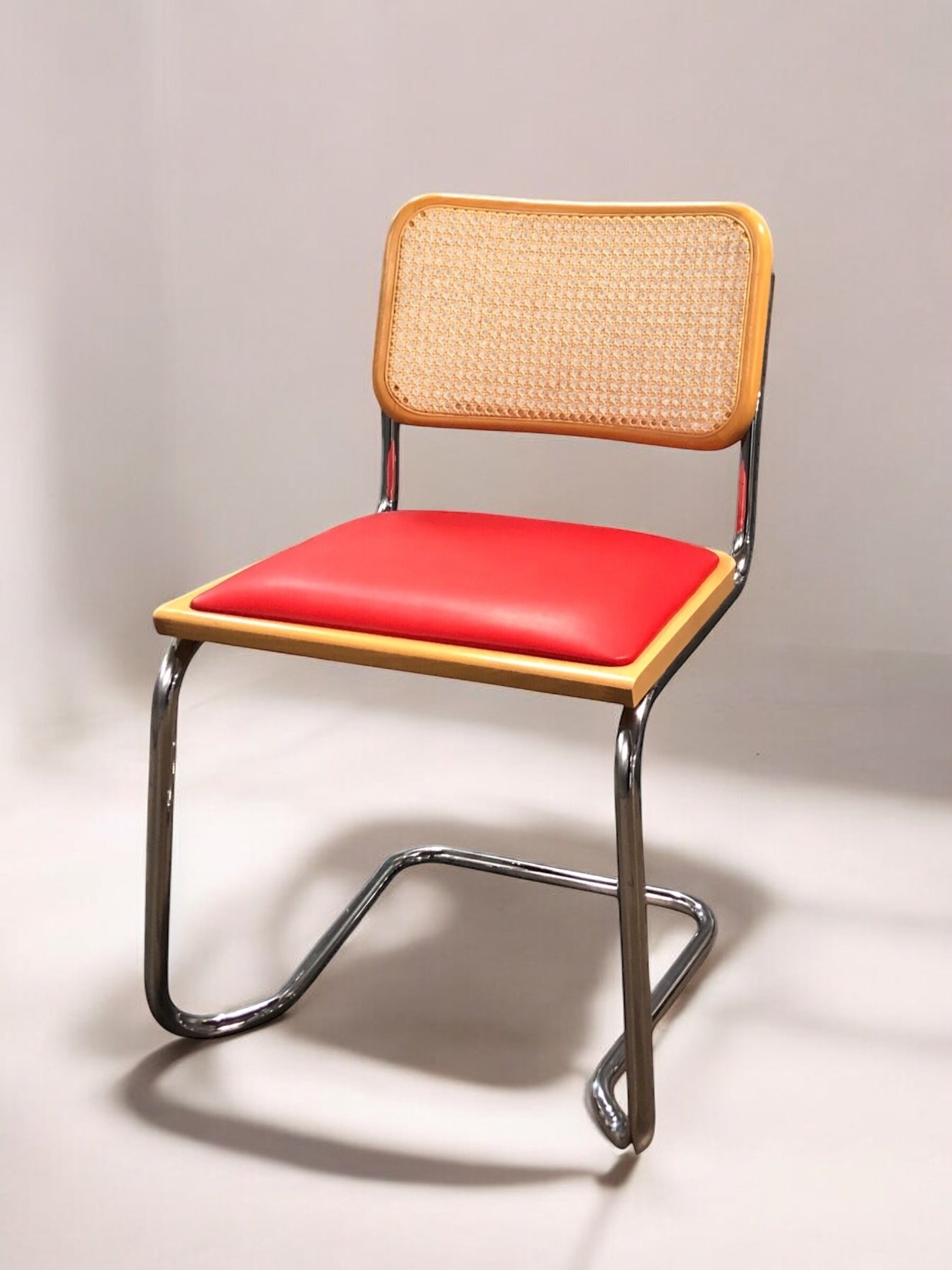 Rottingstol Klassisk Bauhausstol med fodrad röd konstläder sits och rotting rygg.
Sits märkt "Made in italy". 
Bra begagnat skick och stapelbar. Cesca  stol med flätad rotting. Designstol i klassisk stil. 
Designstol Frisvinger karmstol i klassiska design.
Höjd: ca 84,5 cm
Bredd: ca 48 cm
Djup: ca 52cm
Sitthöjd: ca 49 cm