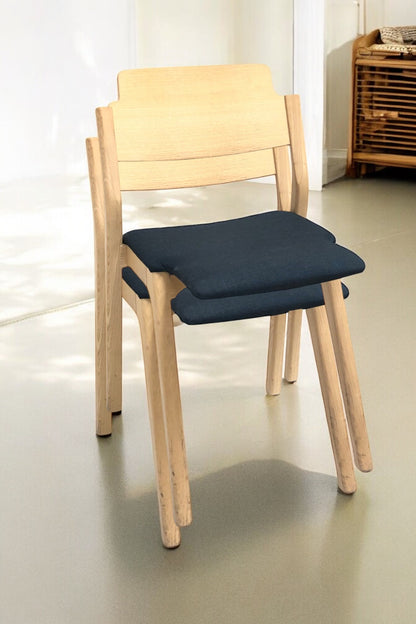 Stapelbar designstol i svensk design i grön/blå färg med ben i ljus ek och modern form – en slitstark, stilren stol perfekt för kök, matsal, kontor, konferensrum och modern skandinavisk inredning.